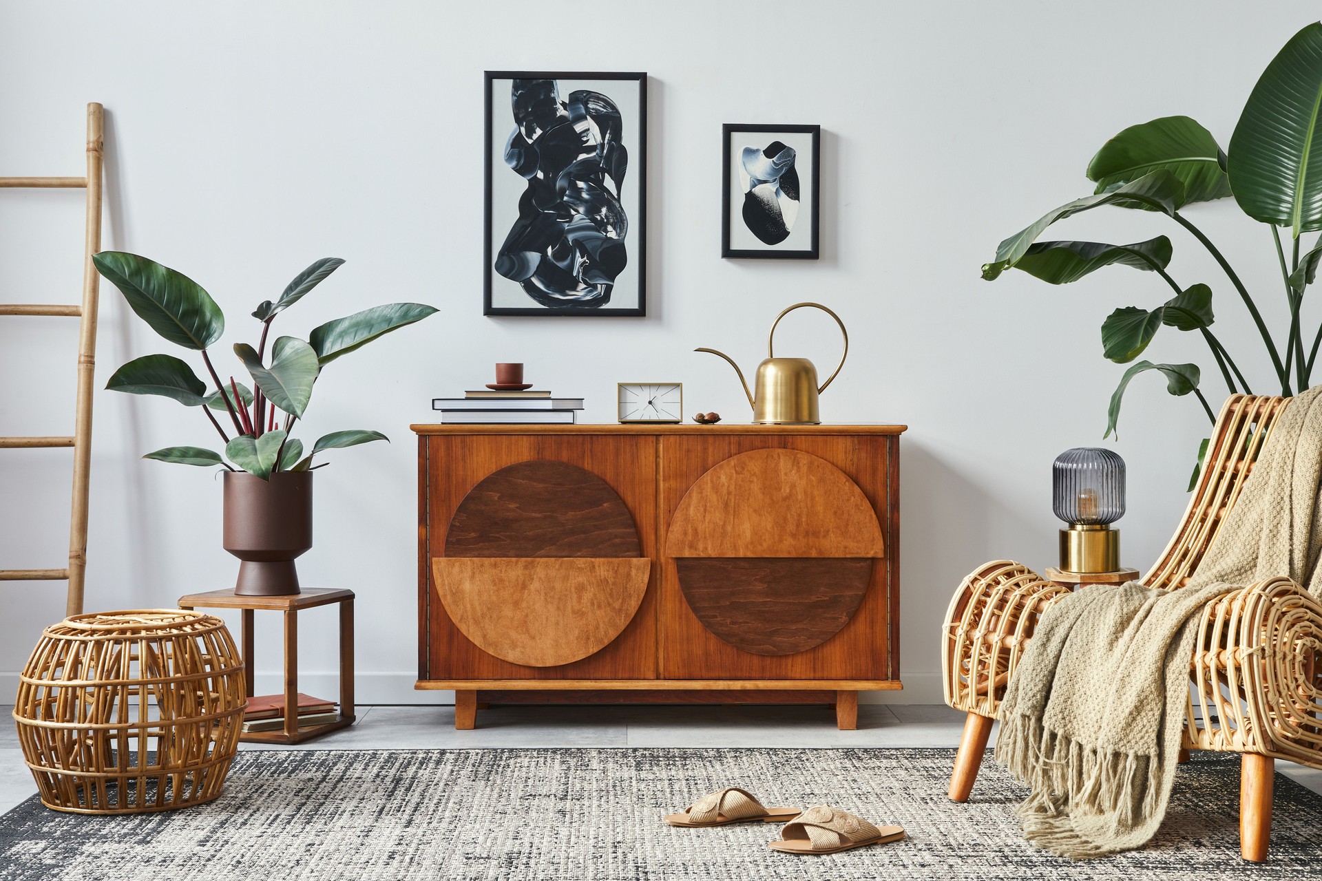 Stylish scandinavian composition of living room with design commode, black mock up poster frames, armchair, wooden stool, book, decoration, plants and personal accessories in modern home decor.