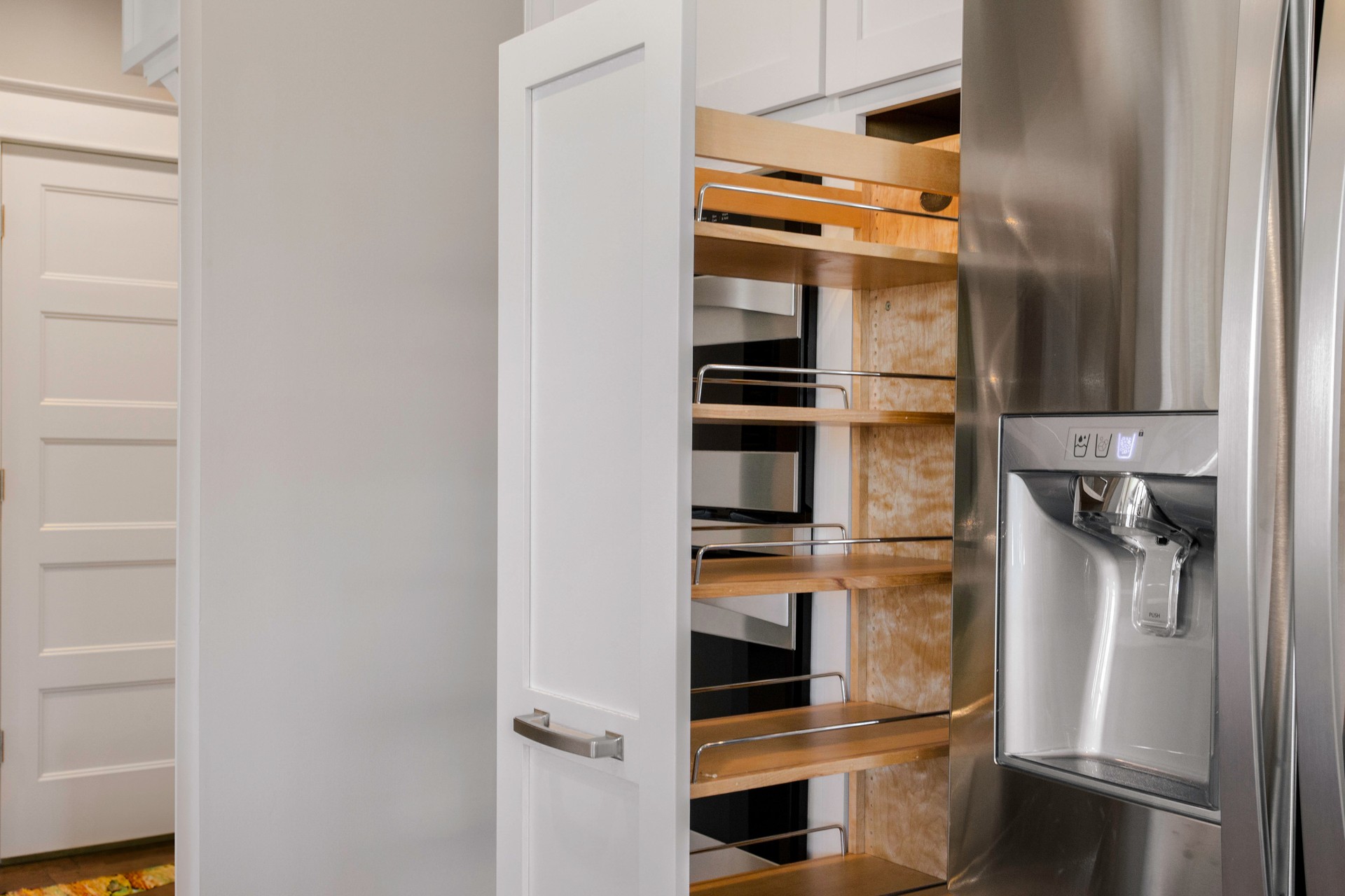 Modern Kitchen With Pull-Out Pantry Shelves And Stainless Steel Fridge.